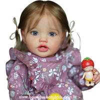Close da Boneca Bebê Reborn Julia com vestido floral lilás, olhos azuis marcantes e brinquedo de morango nas mãos.