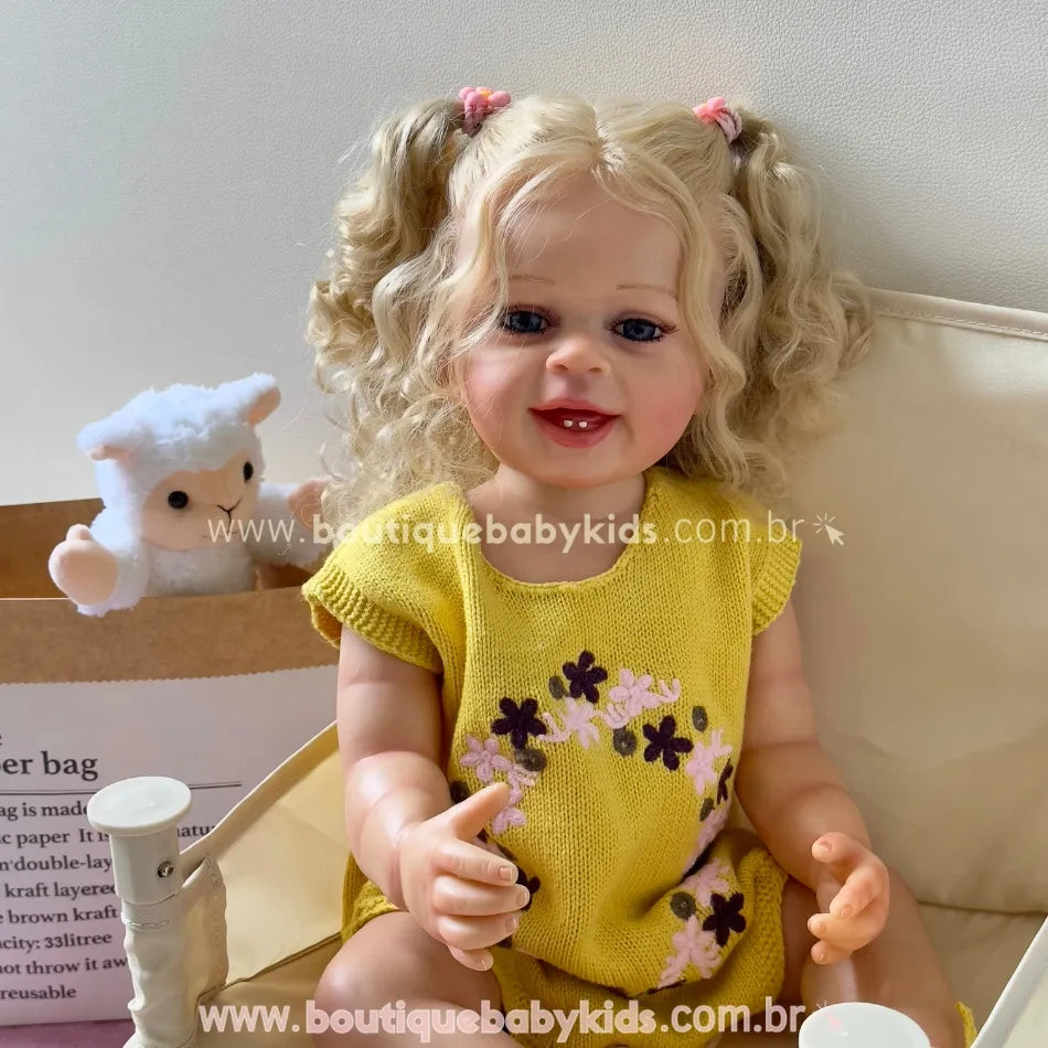 Boneca Lara sentada com um grande sorriso, ao lado de uma caixa com ovelhinha de pelúcia.