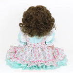 Vista traseira da Boneca Bebê Reborn Maria destacando o volume dos cabelos cacheados e vestido com babados.