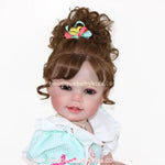 Close do rosto da Boneca Reborn Maria com cabelo preso em coque alto e laço colorido.