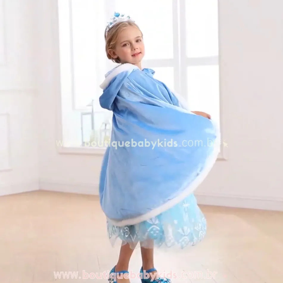 Menina vestindo a capa azul, girando e exibindo o tecido fluído e brilhante, perfeito para brincadeiras encantadas. 