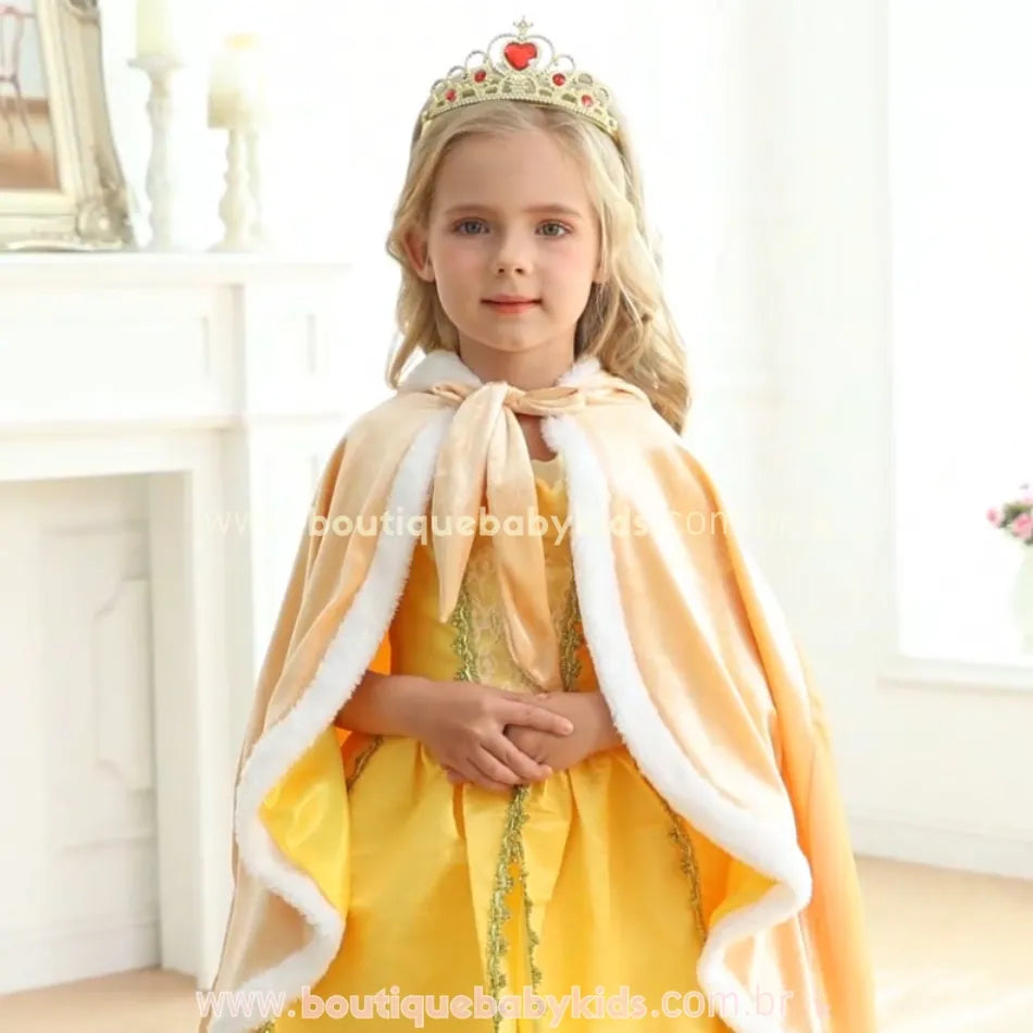 Menina usando a capa dourada sobre um vestido temático, destacando os detalhes da peça e o laço de fechamento. 