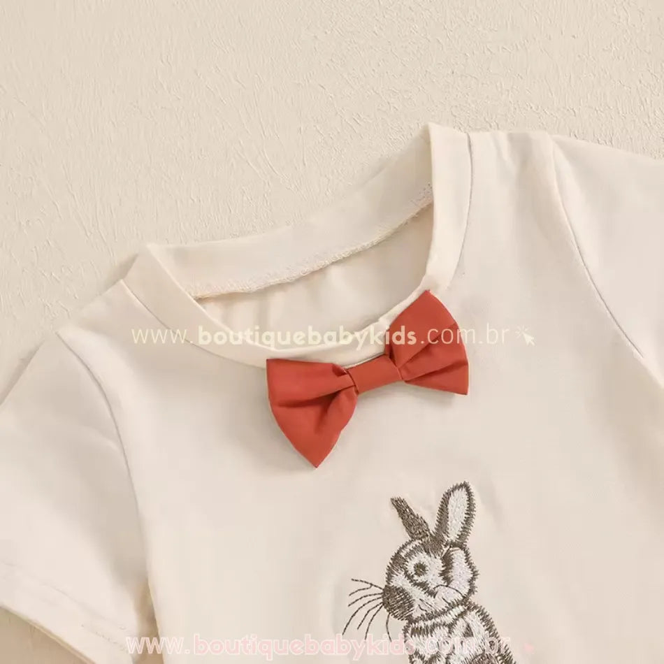Close na gola da camiseta infantil de Páscoa com laço decorativo fixo e bordado detalhado de coelhinho. Tecido suave e respirável, perfeito para ocasiões especiais.