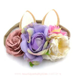 Faixa de coelhinho com flores vibrantes em tons de lilás, rosa e creme, com base elástica confortável, ideal para bebês e crianças pequenas.