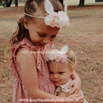 Duas irmãs usando a Faixa Temática Páscoa Jardim da Coelhinha em um momento especial ao ar livre, evidenciando a delicadeza e charme do acessório.