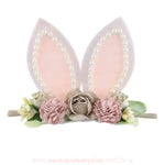 Faixa temática de Páscoa com orelhas de coelho decoradas com pérolas e flores em tons suaves de bege, rosa e verde, criando um visual delicado e encantador.