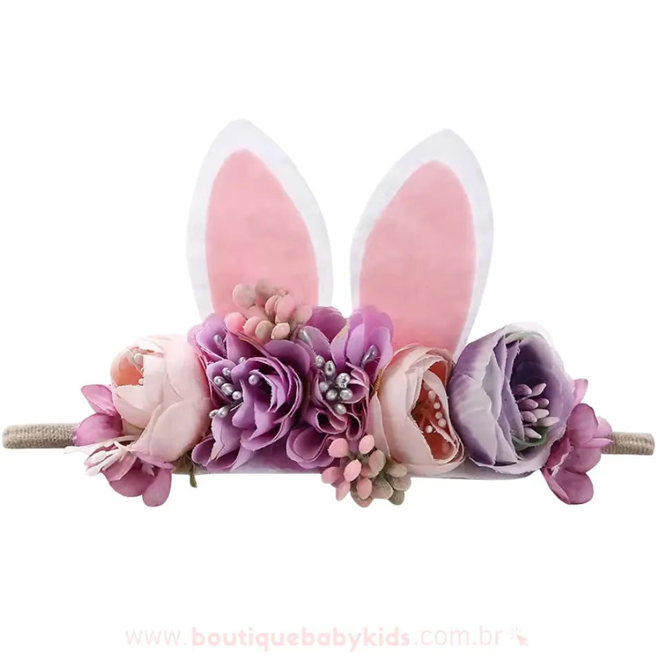 Faixa infantil com detalhes florais em tons de lilás, rosa e lavanda, combinados com orelhinhas de coelho brancas e rosadas, ideal para um look especial de Páscoa.