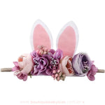 Faixa infantil com detalhes florais em tons de lilás, rosa e lavanda, combinados com orelhinhas de coelho brancas e rosadas, ideal para um look especial de Páscoa.
