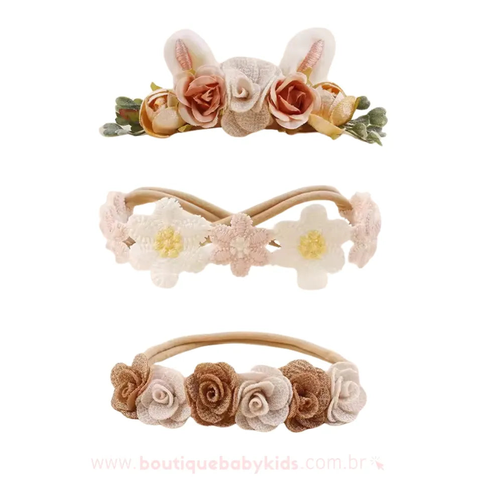 Conjunto de três faixas florais em tons neutros e terrosos, destacando uma faixa com orelhinhas de coelho e flores em tons bege e marrom, uma faixa delicada com flores de renda em tons claros e outra faixa com pequenas rosas em tom marrom e creme.