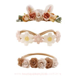 Conjunto de três faixas florais em tons neutros e terrosos, destacando uma faixa com orelhinhas de coelho e flores em tons bege e marrom, uma faixa delicada com flores de renda em tons claros e outra faixa com pequenas rosas em tom marrom e creme.