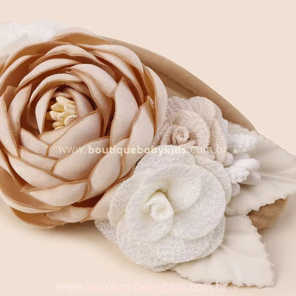 Close-up de faixa floral em tons bege e branco, com flores volumosas e detalhes sofisticados em tecido, criando um efeito delicado e elegante.