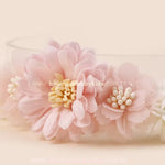 Detalhe de faixa floral rosa com flores em camadas e apliques delicados no centro, trazendo um visual romântico e delicado.