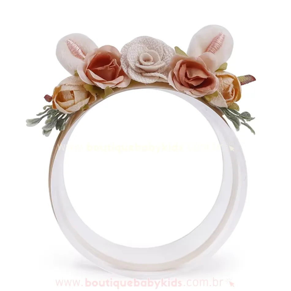 Uma delicada faixa infantil decorada com pequenas rosas em tons de bege e marrom claro, folhas verdes sutis e duas orelhinhas de coelhinho aveludadas. A base da faixa é flexível e confortável.