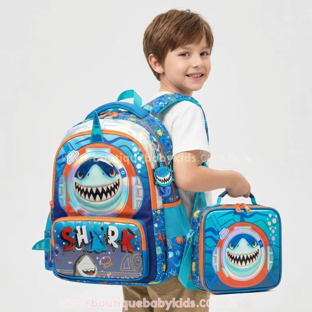 Menino usando o kit escolar Tubarão, com a mochila azul nas costas e segurando a lancheira térmica pela alça de mão.