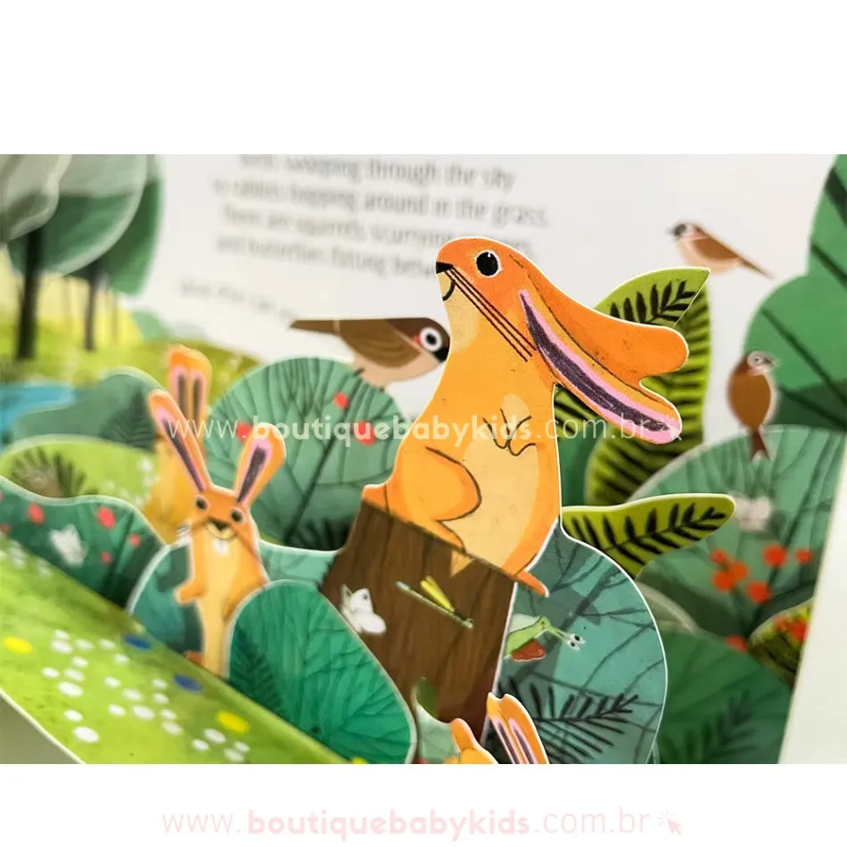 Close-up de um dos elementos pop-up do livro Pop-Up Nature, mostrando um coelhinho laranja em destaque sobre um tronco, com outros animais ao fundo. Os detalhes tridimensionais tornam a leitura ainda mais imersiva.