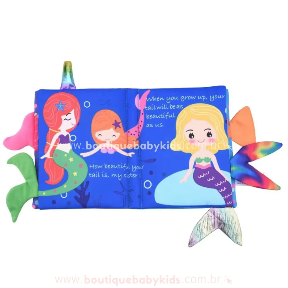 Página do livro sensorial exibindo três sereias em tons vibrantes, com caudas coloridas e detalhes subaquáticos. As frases em inglês compõem a história, incentivando a leitura e o aprendizado da língua.