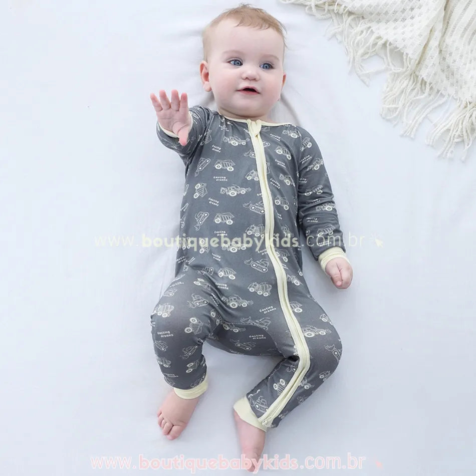 Bebê deitado de barriga para cima com o macacão aberto na perna, mostrando a praticidade do zíper.