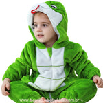 Criança sentada no chão com expressão atenta, vestindo o macacão de serpente verde com capuz divertido. 