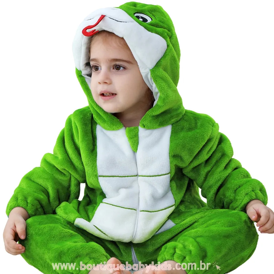 Criança sentada no chão com expressão atenta, vestindo o macacão de serpente verde com capuz divertido. 