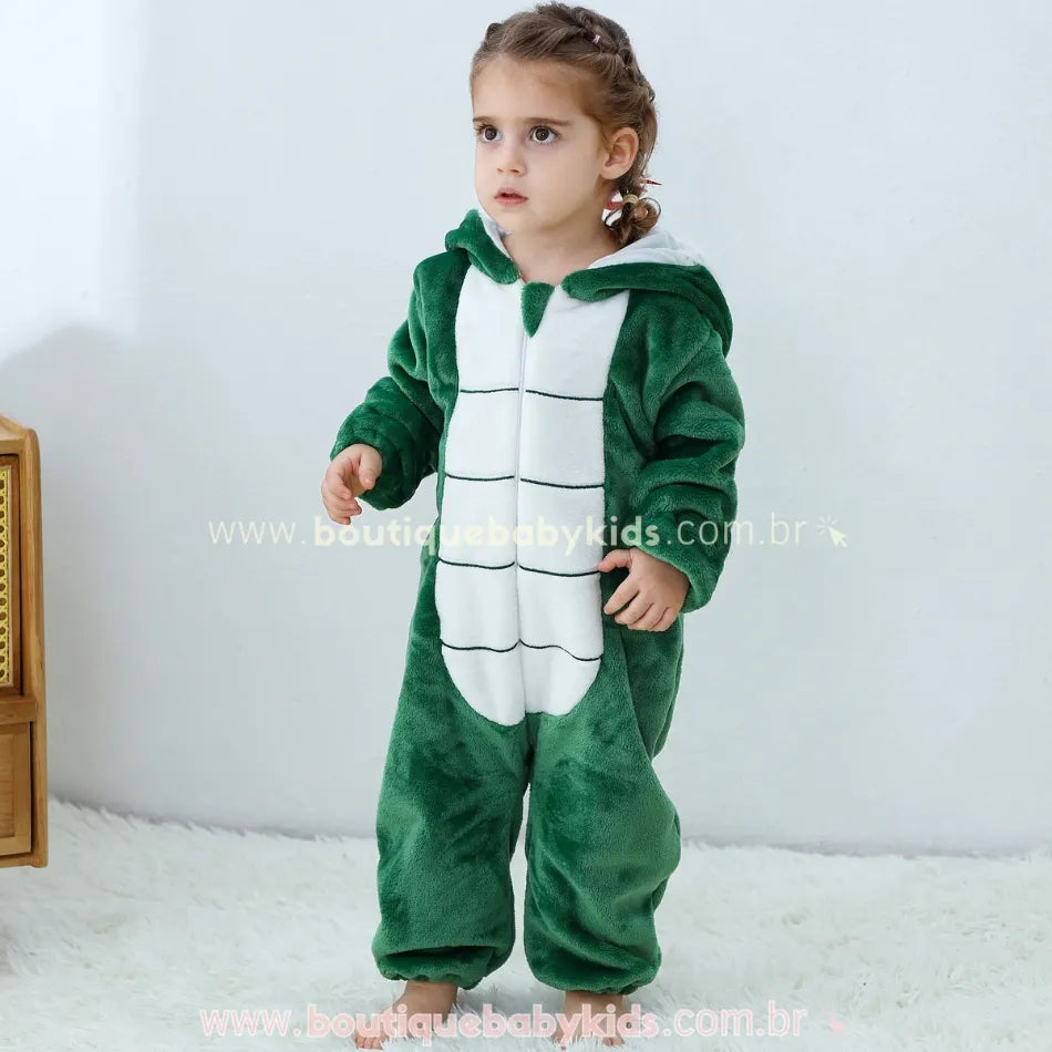 Criança em pé usando o macacão fantasia de serpente verde, com capuz com rosto de cobra e linguinha vermelha, mostrando a parte frontal da peça. 