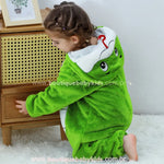 Criança agachada de lado, exibindo o capuz com rosto de serpente bordado e expressão simpática. 