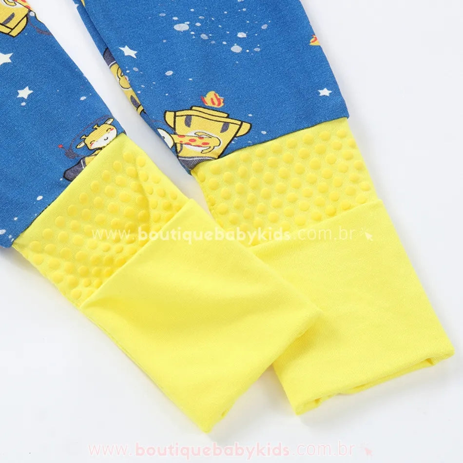 Detalhe dos punhos antiderrapantes e dobráveis do macacão bebê em fibra de bambu, com estampa de girafinhas astronautas.