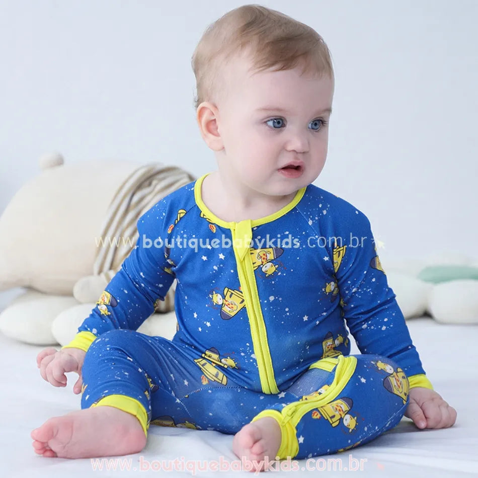 Bebê sorridente com macacão em fibra de bambu, leve e respirável, com estampa de girafinhas no universo.