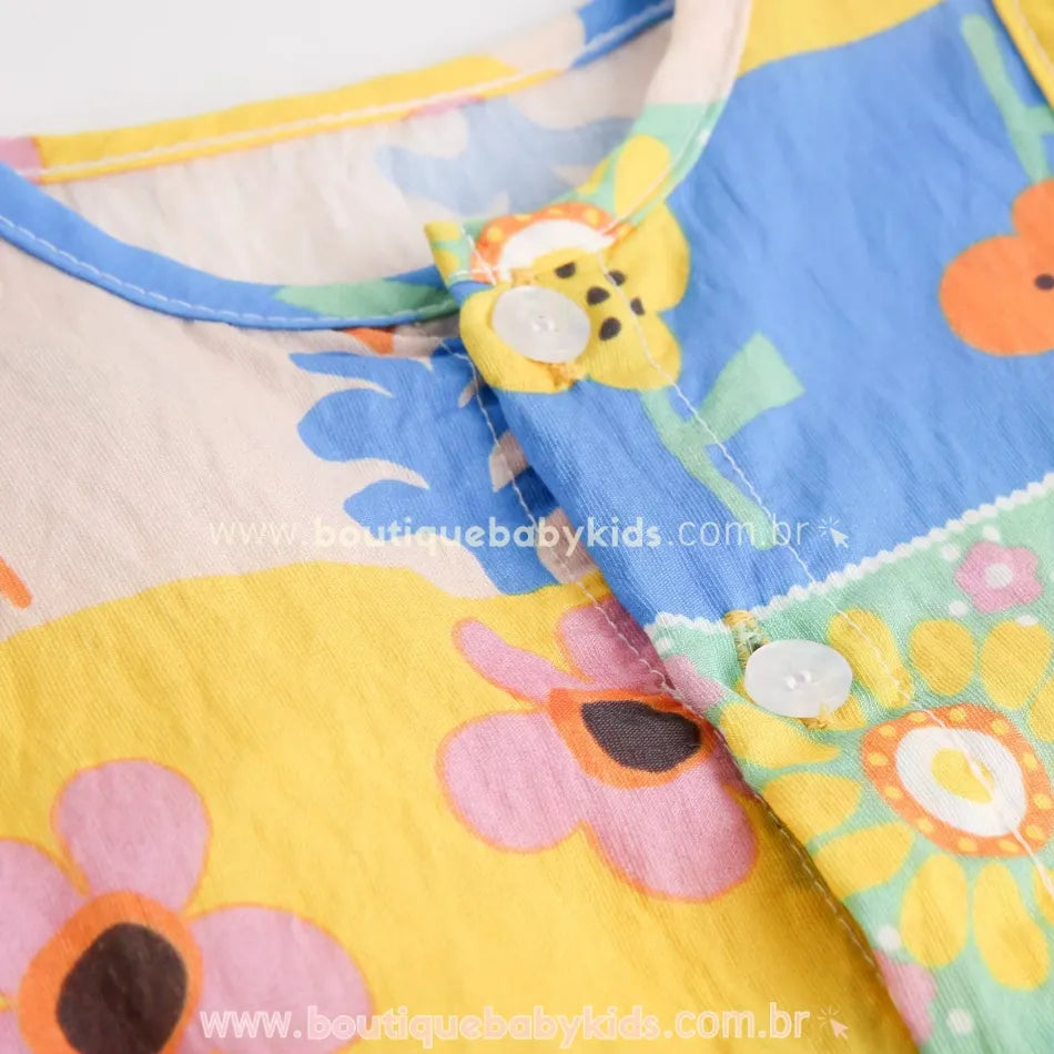Gola arredondada com fechamento frontal por botões no macacão bebê estampado.
