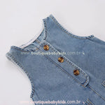 Close-up dos botões frontais do macacão bebê jeans, destacando o acabamento refinado e o design retrô.