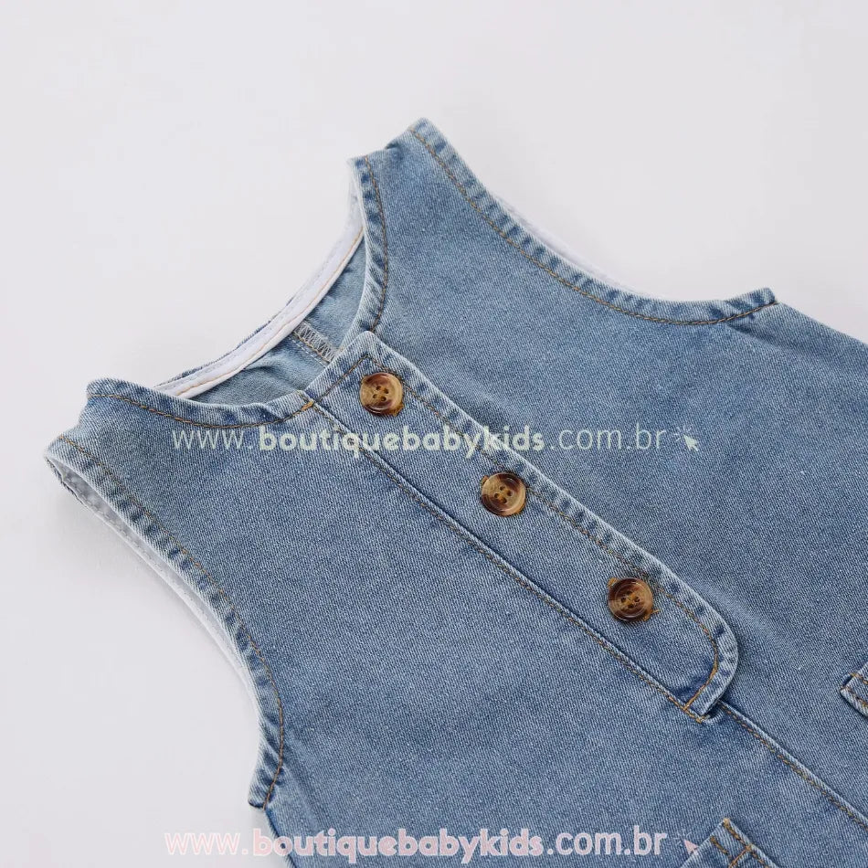 Close-up dos botões frontais do macacão bebê jeans, destacando o acabamento refinado e o design retrô.