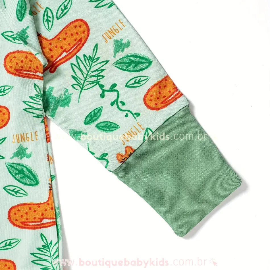 Detalhe da manga do macacão infantil com punho dobrável verde e estampa de oncinha laranja sobre fundo verde-claro com folhagens.