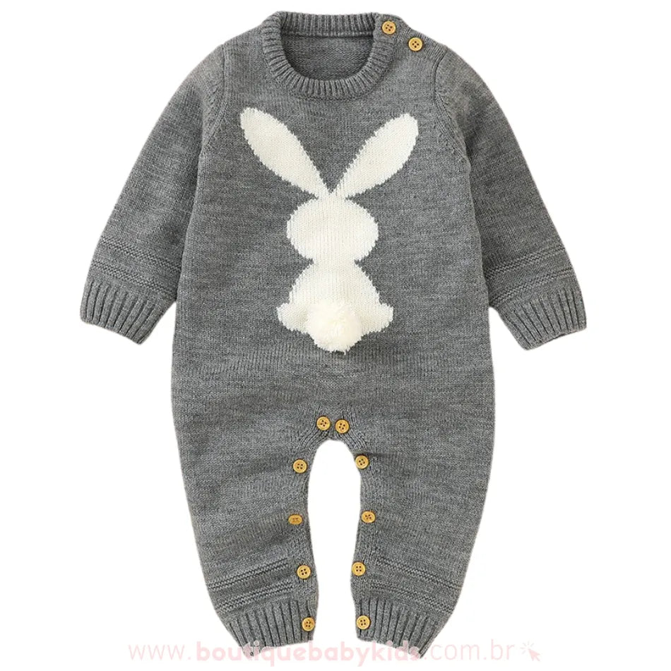 Macacão bebê tricot coelhinho na cor cinza, com estampa de coelho branco na parte frontal e detalhe de rabinho pompom. Modelo com mangas longas e botões em madeira nos ombros e entrepernas. 