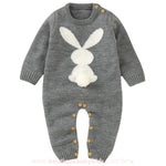 Macacão bebê tricot coelhinho na cor cinza, com estampa de coelho branco na parte frontal e detalhe de rabinho pompom. Modelo com mangas longas e botões em madeira nos ombros e entrepernas. 