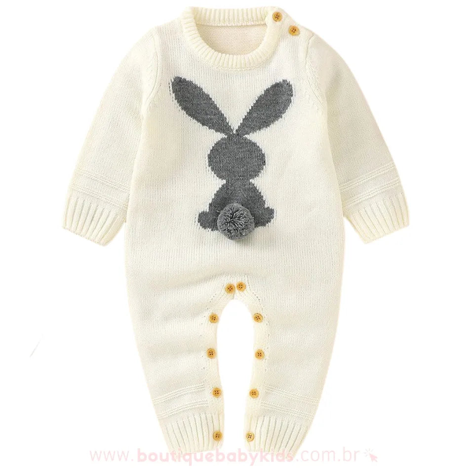 Macacão bebê tricot coelhinho na cor branca, com estampa de coelho cinza e rabinho pompom. Possui botões em madeira nos ombros e entrepernas, garantindo praticidade. 