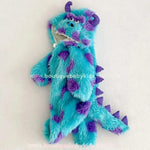 Vista lateral do macacão Sulley com cauda em espinhos roxos e capuz com chifres