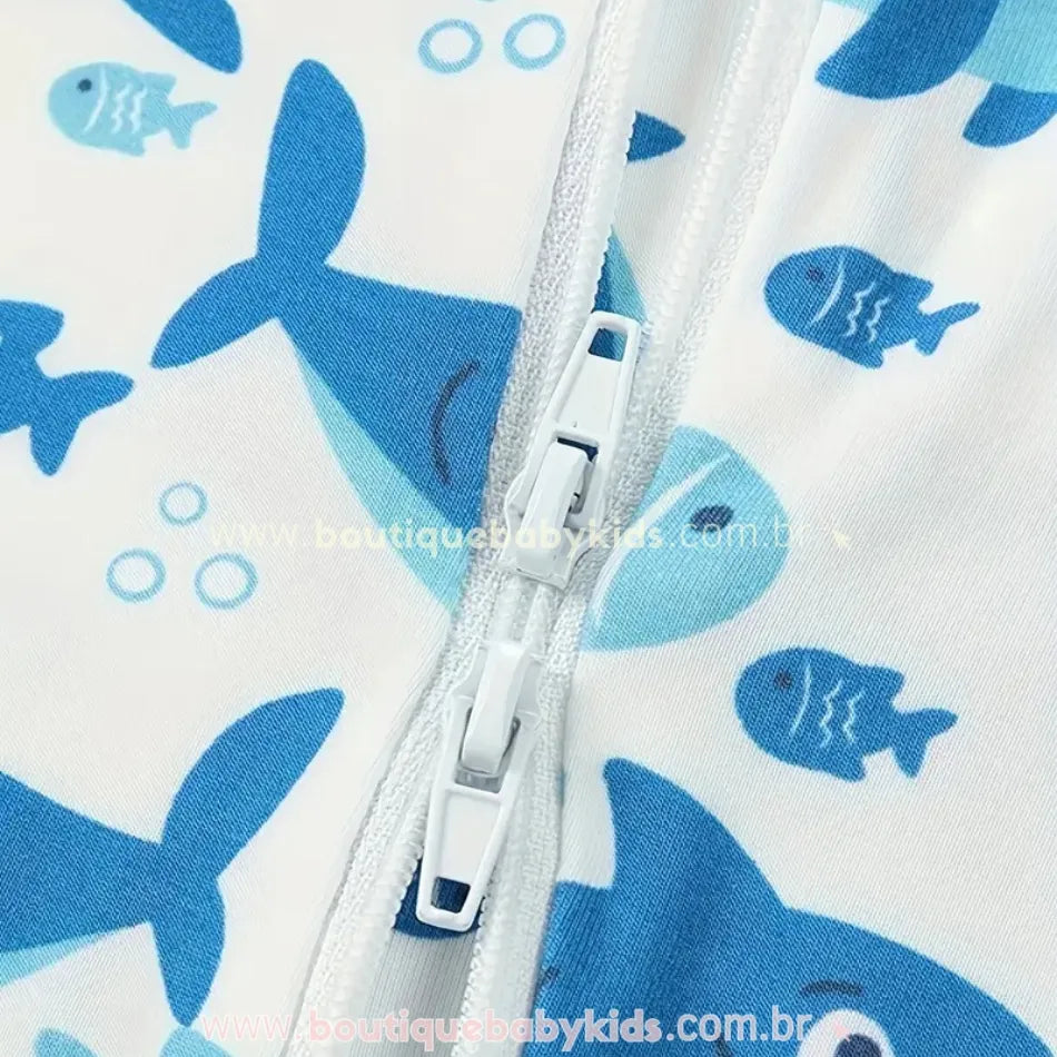 Detalhe do zíper branco duplo do macaquinho com estampa de tubarões e peixinhos azuis, em tecido de fibra de bambu
