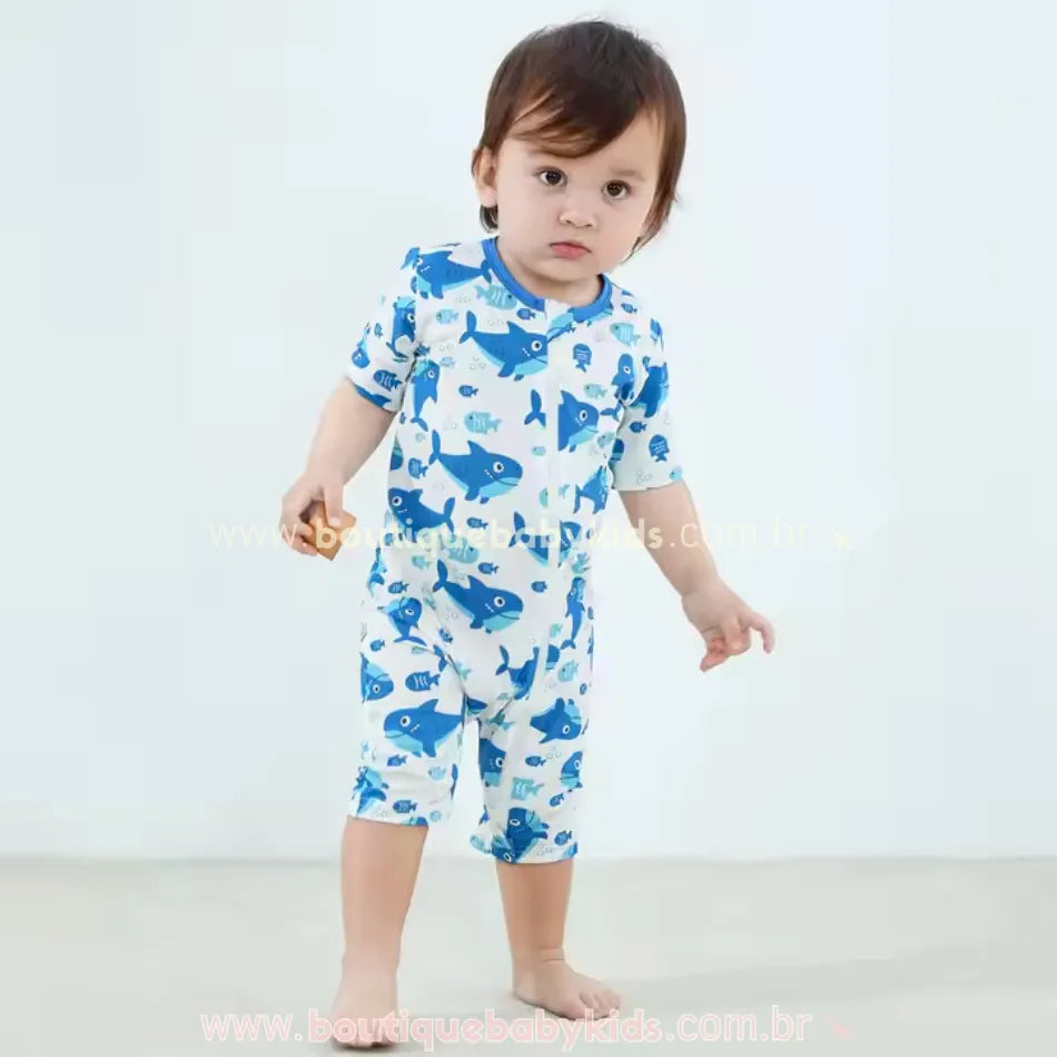 Criança em pé usando o macaquinho de fibra de bambu com estampa de tubarões azuis