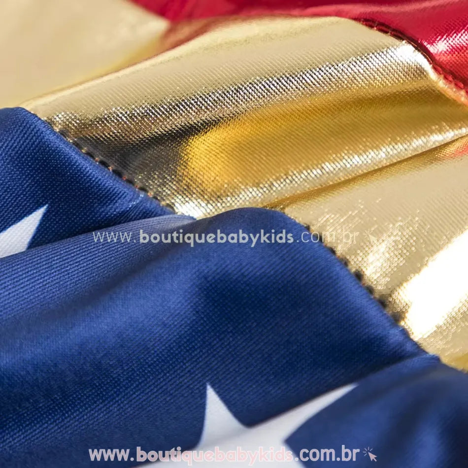 Close-up do tecido do Maiô Infantil Heroína Mulher Maravilha, mostrando o acabamento brilhante da faixa dourada, parte azul com estrelas brancas e detalhes da costura.