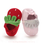 Pantufinhas de bebê nas cores vermelha e rosa, exibindo um design inspirado em morangos com acabamento macio e elástico confortável na abertura.