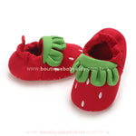 Dupla de pantufinhas vermelhas de morango, exibindo a modelagem arredondada e detalhes encantadores na parte superior. 