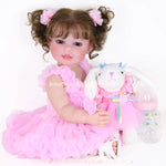 Vídeo da Boneca Bebê Reborn Rebecca 55 cm sentada com vestido rosa, segurando coelhinha de pelúcia, chupeta magnética e mamadeira ao lado, mostrando detalhes realistas do rosto, cabelos e movimentos.