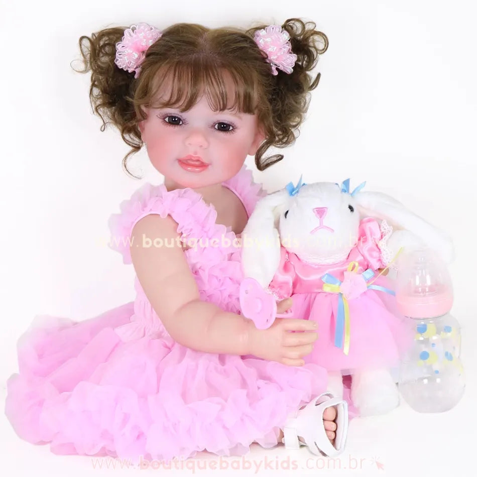 Vídeo da Boneca Bebê Reborn Rebecca 55 cm sentada com vestido rosa, segurando coelhinha de pelúcia, chupeta magnética e mamadeira ao lado, mostrando detalhes realistas do rosto, cabelos e movimentos.