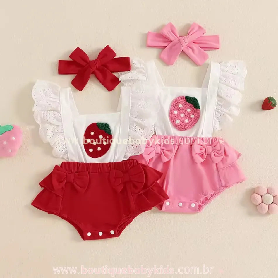 Duas versões do romper bordado de moranguinho, uma vermelha e outra rosa, ambas com babados e faixas combinando.