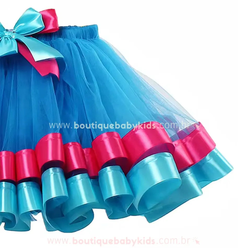 Detalhe da barra da saia infantil temática Poppy Trolls, feita de tule azul vibrante com acabamento em fitas largas de cetim rosa e azul.