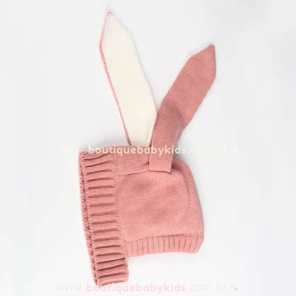 Touca rosa bebê de tricot  com orelhinhas longas de coelho, exibindo a elasticidade e os detalhes da costura.