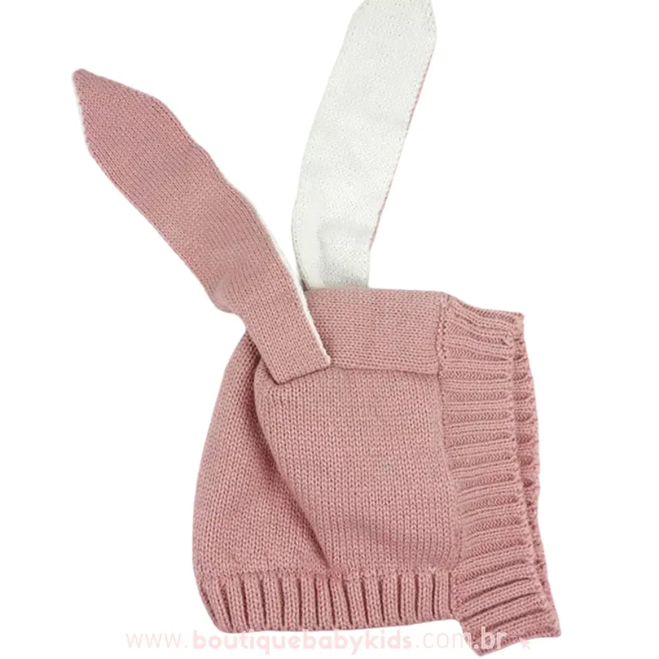Touca rosa claro com orelhas de coelho estendidas para cima, mostrando os detalhes do tricot e a parte interna das orelhas em tom mais claro.