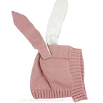 Touca rosa claro com orelhas de coelho estendidas para cima, mostrando os detalhes do tricot e a parte interna das orelhas em tom mais claro.