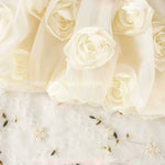 Detalhe das rosas brancas em relevo aplicadas na saia do vestido infantil.