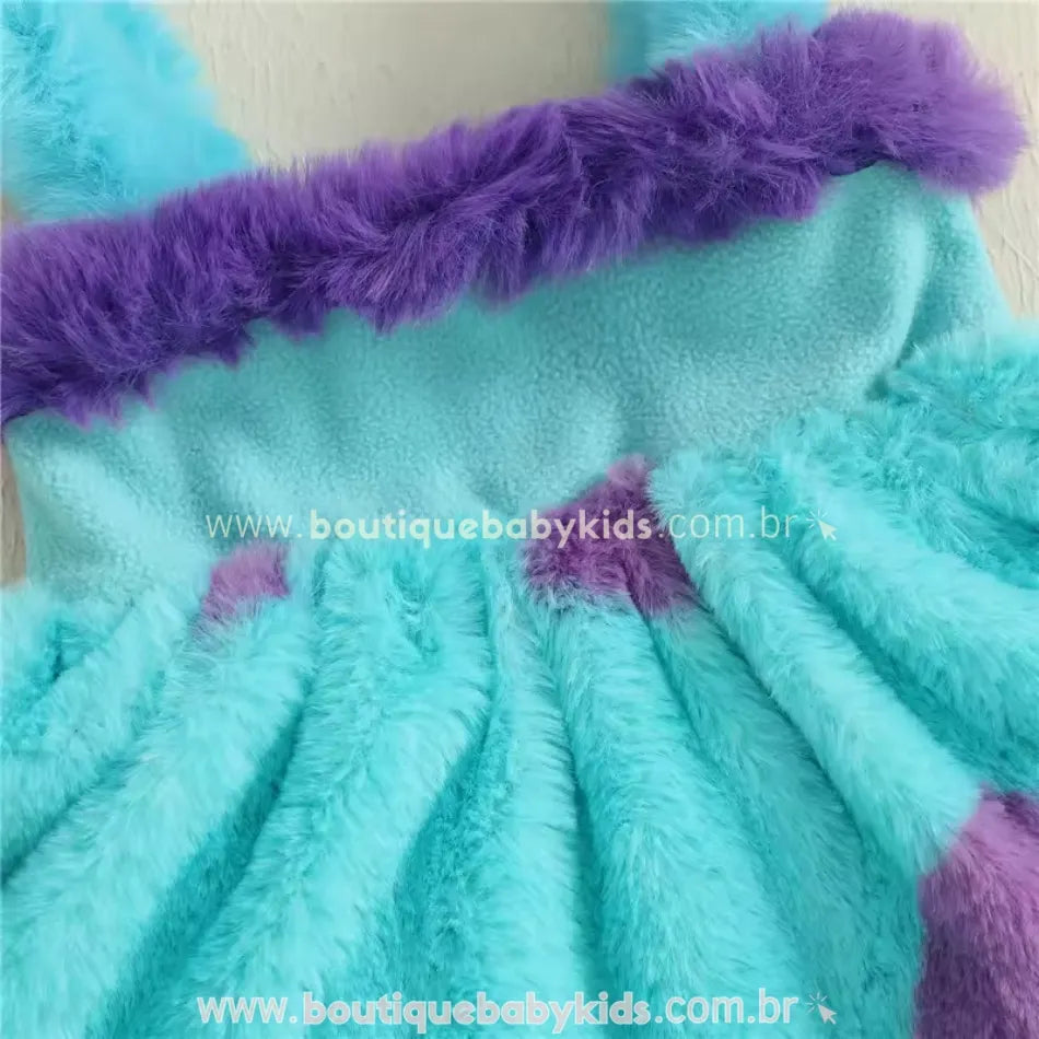 Close na região do peitinho do vestido Sulley, com acabamento em pelúcia roxa e alcinhas peluciadas azuis.