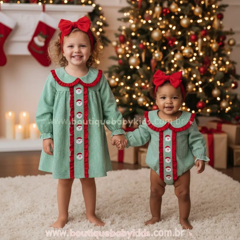 Irmãs vestindo Body e Vestido de Natal Clássico Xadrez Verde Bordado Papai Noel com Faixa de pé em tapete claro de mãos dadas com cenário natalino - Boutique Baby Kids